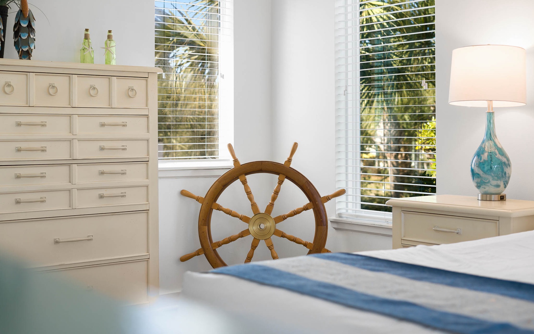 Your coastal bedroom features nautical charm with a ship's wheel centerpiece, tropical views, and soothing ocean-inspired decor.