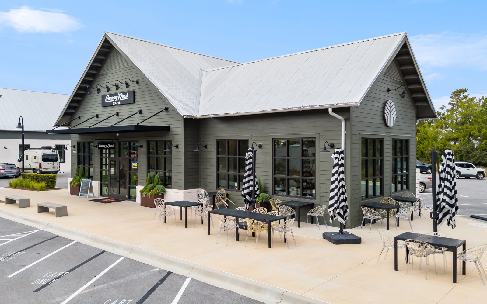 Modern dining establishment with outdoor patio seating, featuring contemporary architecture and convenient parking in a well-designed commercial area.