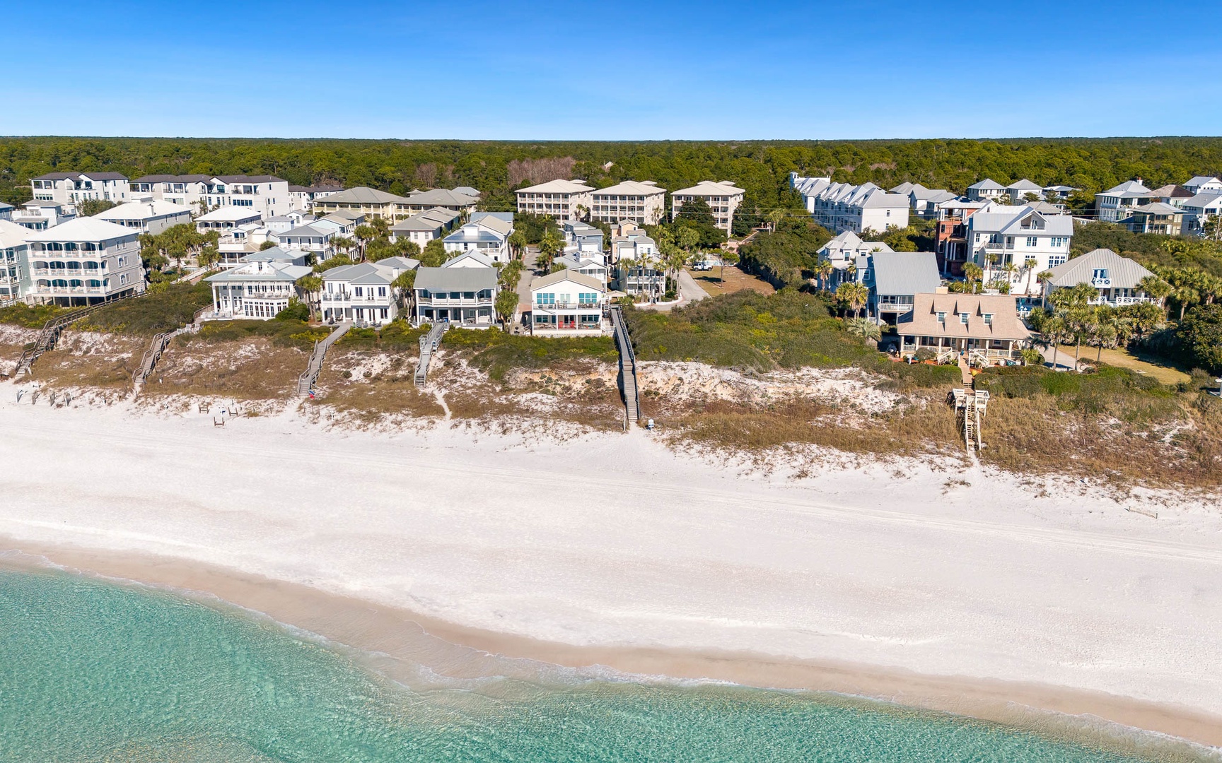 Stunning beachfront community with pristine white sand and crystal-clear turquoise waters stretching along the coastline.