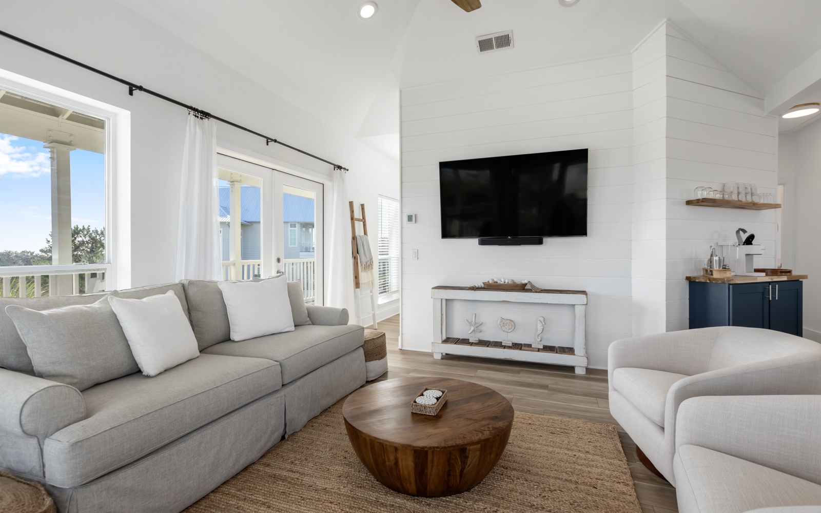 Sink into plush sofas in your bright coastal living room, where natural light streams through large windows and modern coastal charm awaits your relaxation.