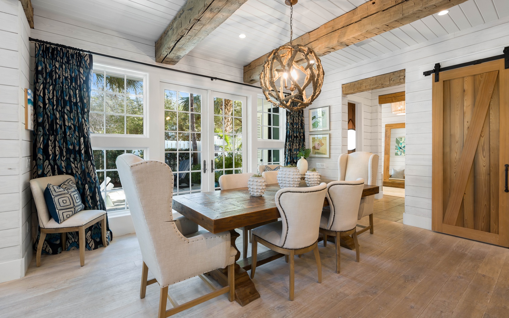 Gather around this elegant dining table where rustic beams meet coastal charm, creating the perfect backdrop for memorable meals.