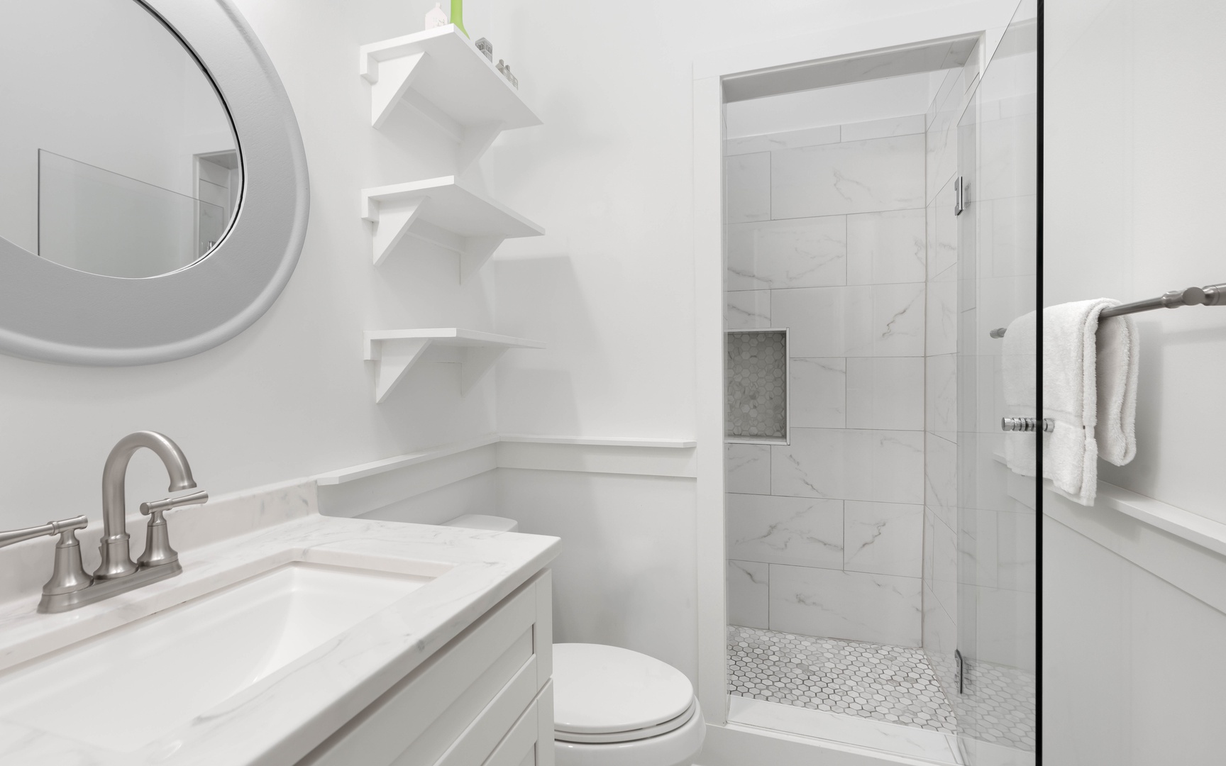 Pristine marble bathroom featuring a luxurious walk-in shower and elegant built-in shelving for your comfort.