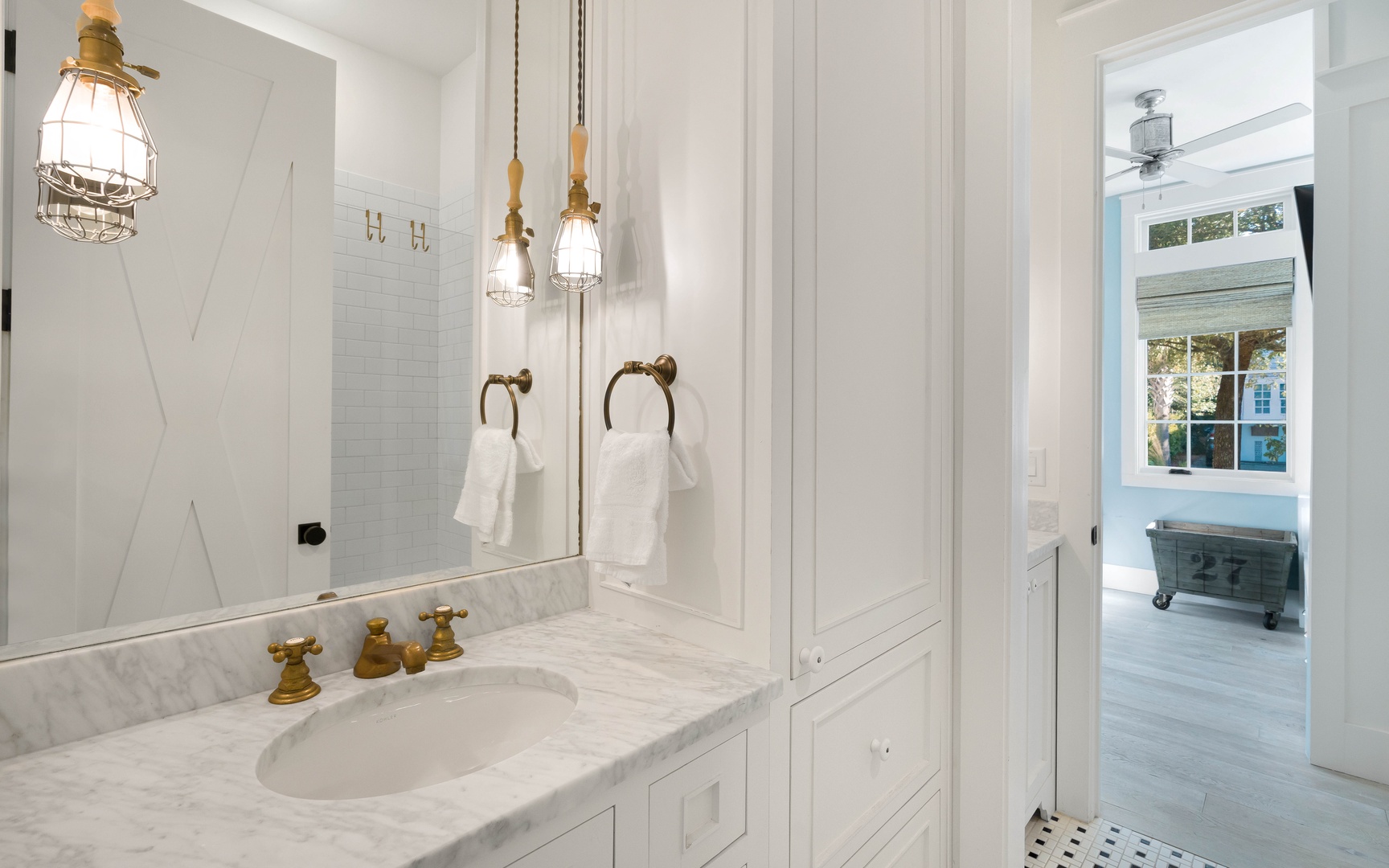 Refresh in your elegantly appointed bathroom with marble counters, brass fixtures, and charming nautical lighting that creates a spa-like atmosphere.