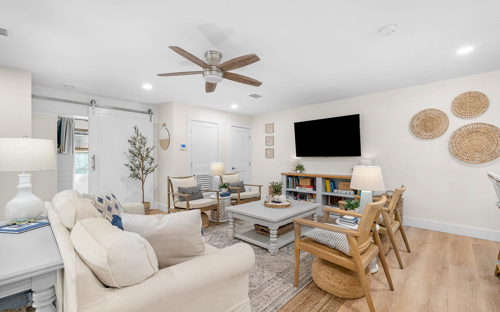 Unwind in your bright, coastal-inspired living room with cozy seating, warm wood accents, and entertainment center—perfect for relaxing after beach days.