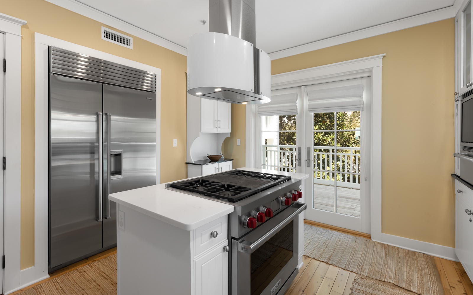 Your gourmet kitchen awaits with professional-grade appliances and warm natural light streaming through French doors to your private balcony.