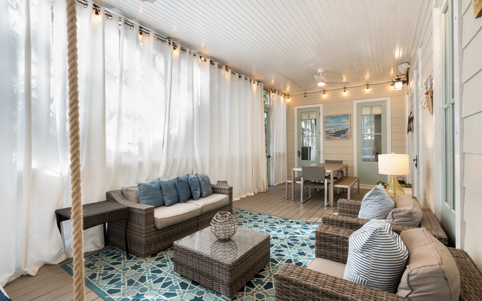 Your private porch retreat features cozy wicker seating, soft nautical pillows, and twinkling string lights creating the perfect spot to unwind.
