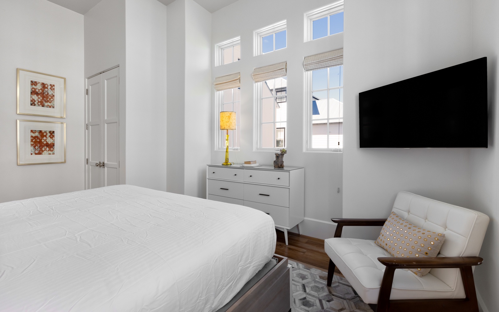 Unwind in your bright, modern bedroom featuring crisp white linens, stylish furnishings, and large windows that flood the space with natural light.
