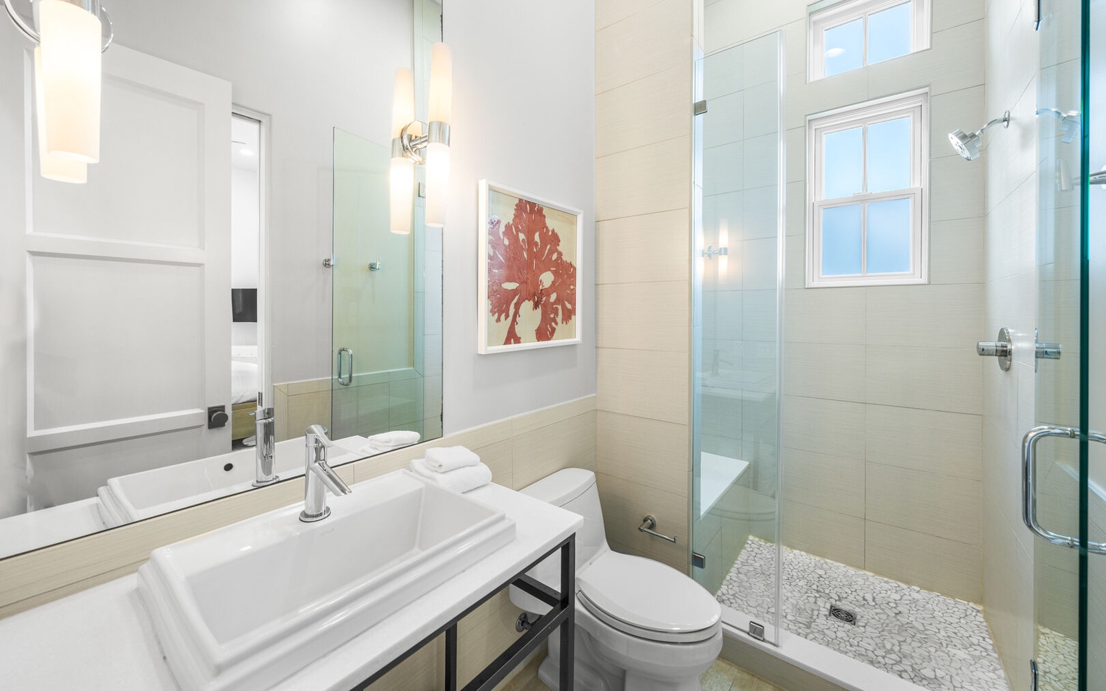 Step into your sleek modern bathroom with glass shower, pristine fixtures, and coral artwork for a refined retreat.