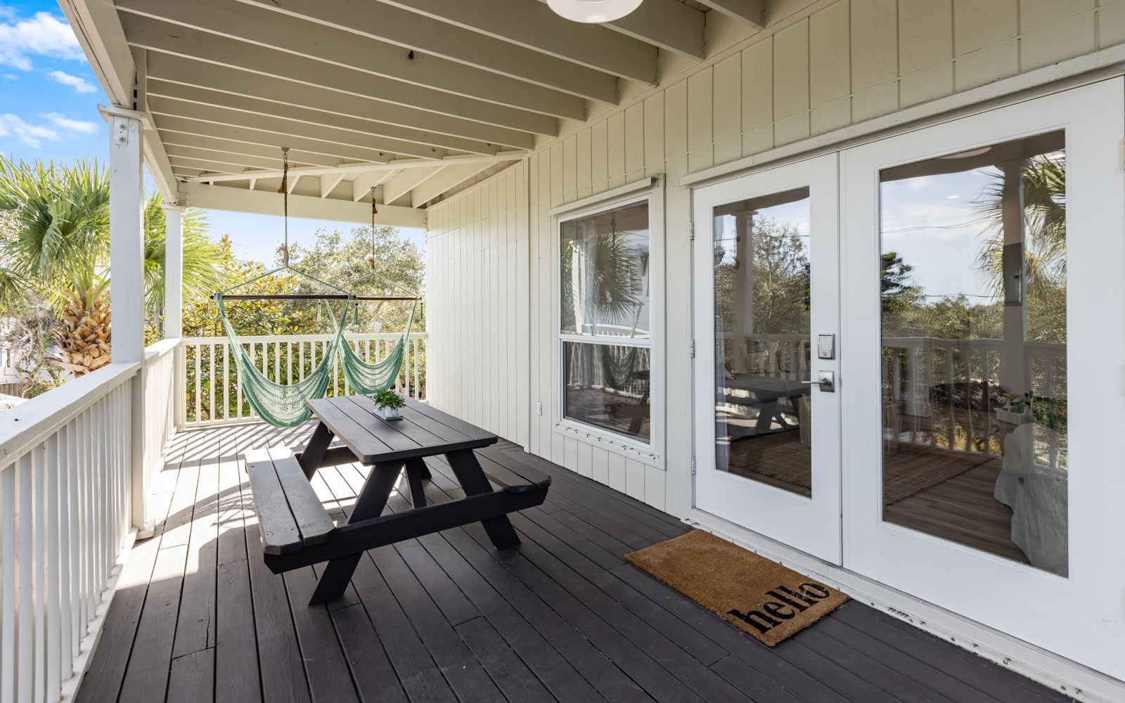 Your private covered deck invites relaxation with a picnic table, hammock chair, and tropical palm views beyond.