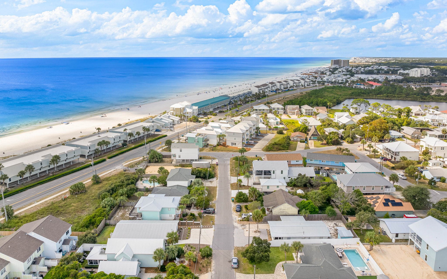 Aerial view of beachfront community with pristine sandy coastline and turquoise waters stretching to the horizon.