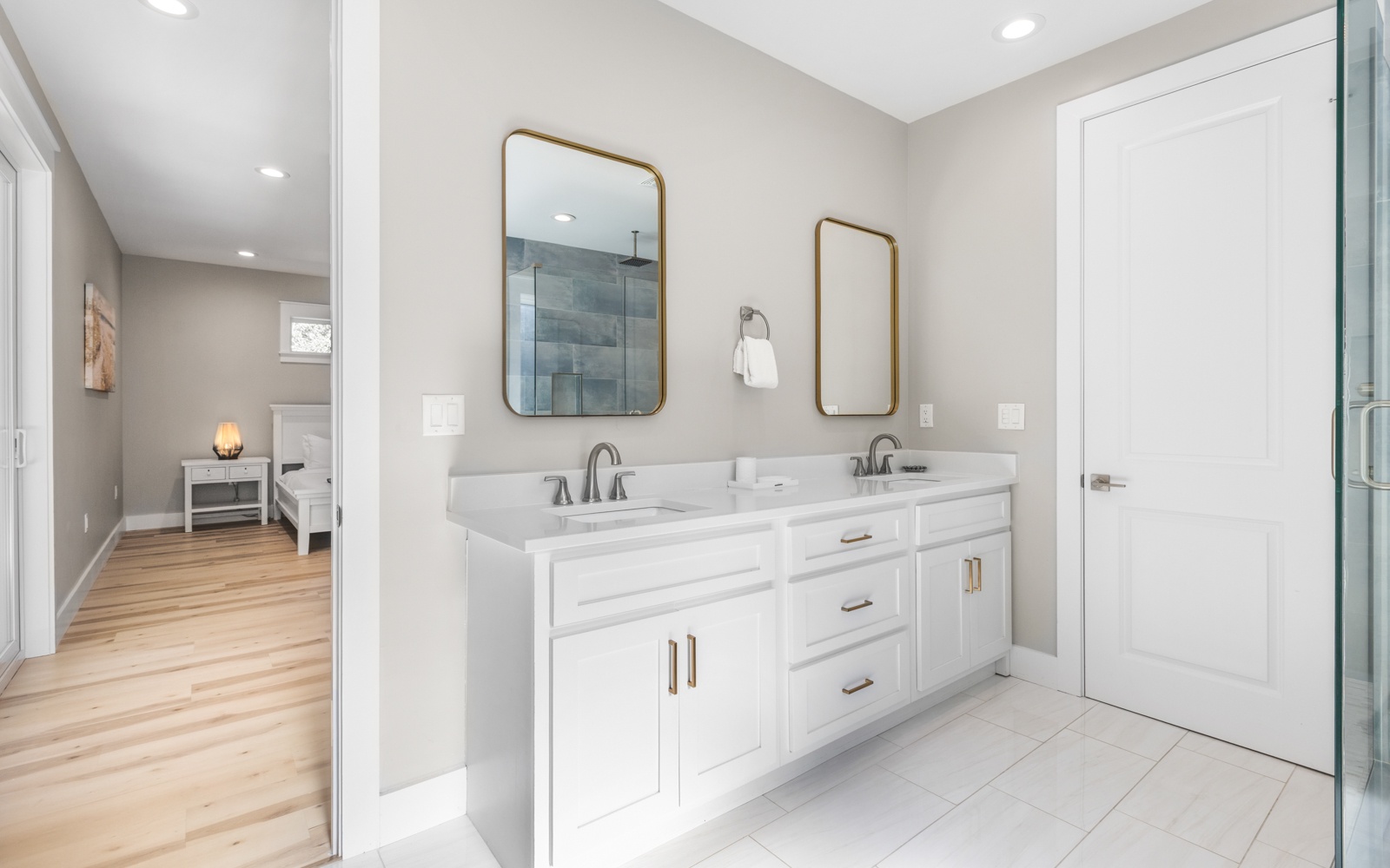 Freshen up in your pristine bathroom with dual vanities, elegant brass mirrors, and a spacious glass shower.