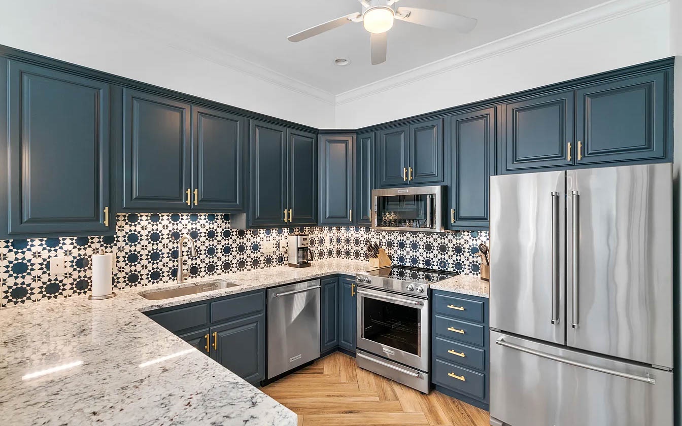 Create culinary magic in this stunning kitchen featuring elegant blue cabinetry, gleaming granite counters, and stainless steel appliances.