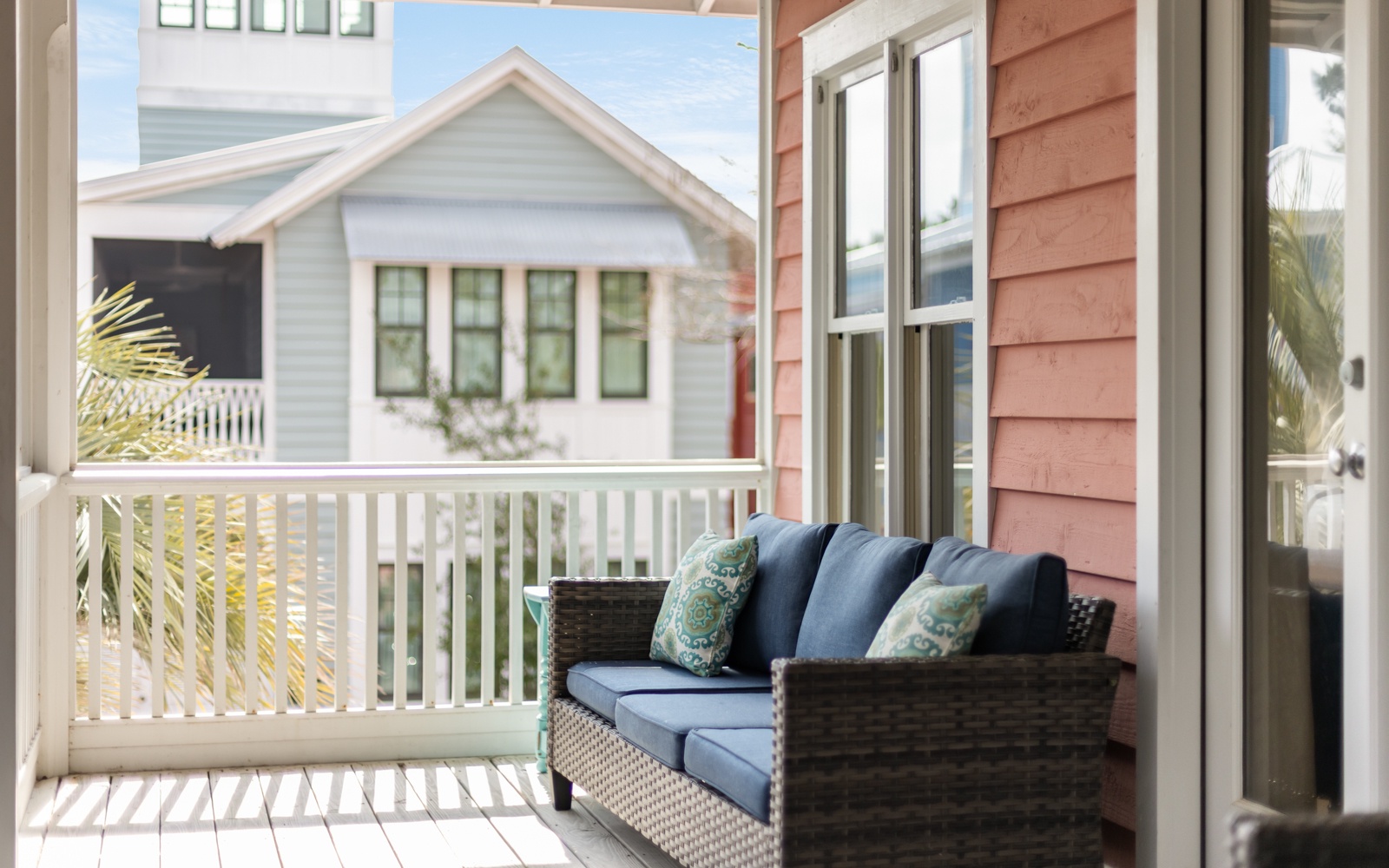 Step out onto your private balcony and sink into plush wicker seating with soft blue cushions and tropical-patterned pillows.