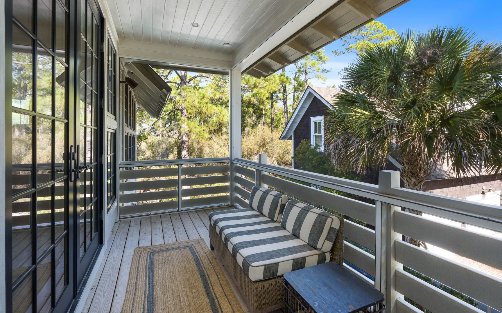 Step onto your private covered balcony with striped cushioned seating, where you can unwind while enjoying peaceful views of neighboring homes and lush palm trees.