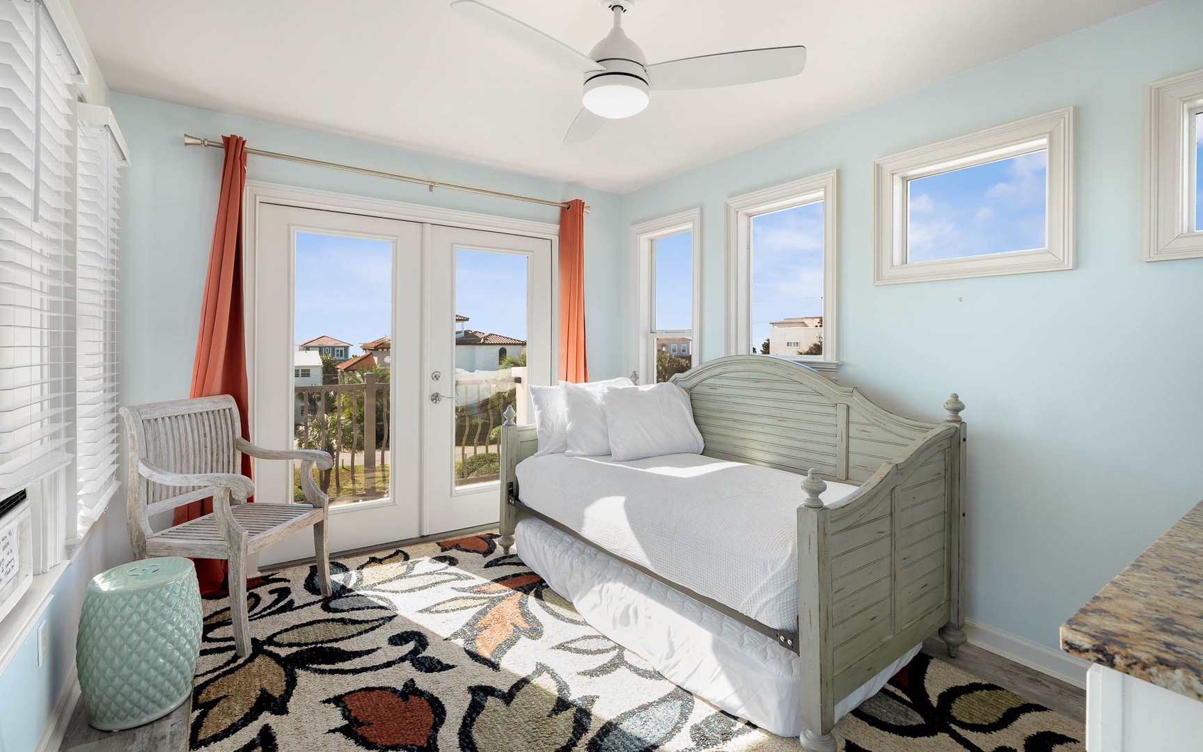Relax in your bright coastal retreat with serene blue walls, comfy daybed, and French doors opening to your private balcony.