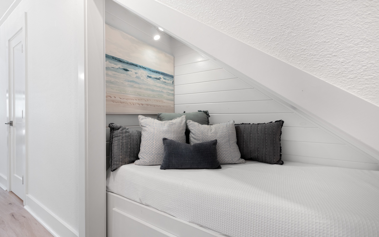 Cozy nook where you can unwind with soft textures and coastal charm tucked beneath the sloped ceiling.
