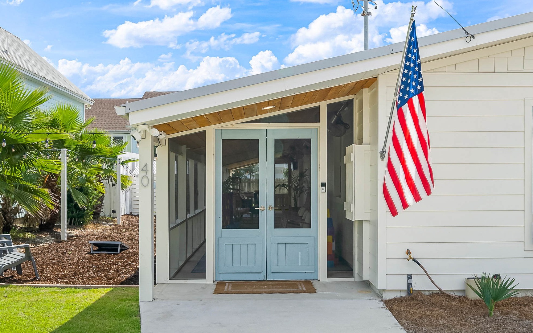 Modern beach house with covered entry and tropical landscaping in a quiet residential area.
