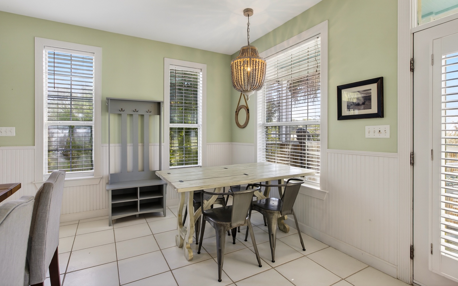 Gather around your bright dining nook with farmhouse charm, featuring a rustic table surrounded by windows that fill the space with natural light.