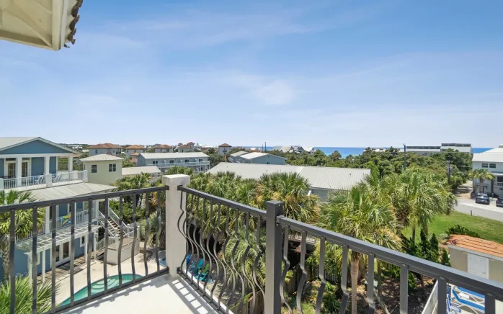 Coastal views stretch across palm-lined neighborhoods from this elevated balcony, offering glimpses of blue waters beyond.