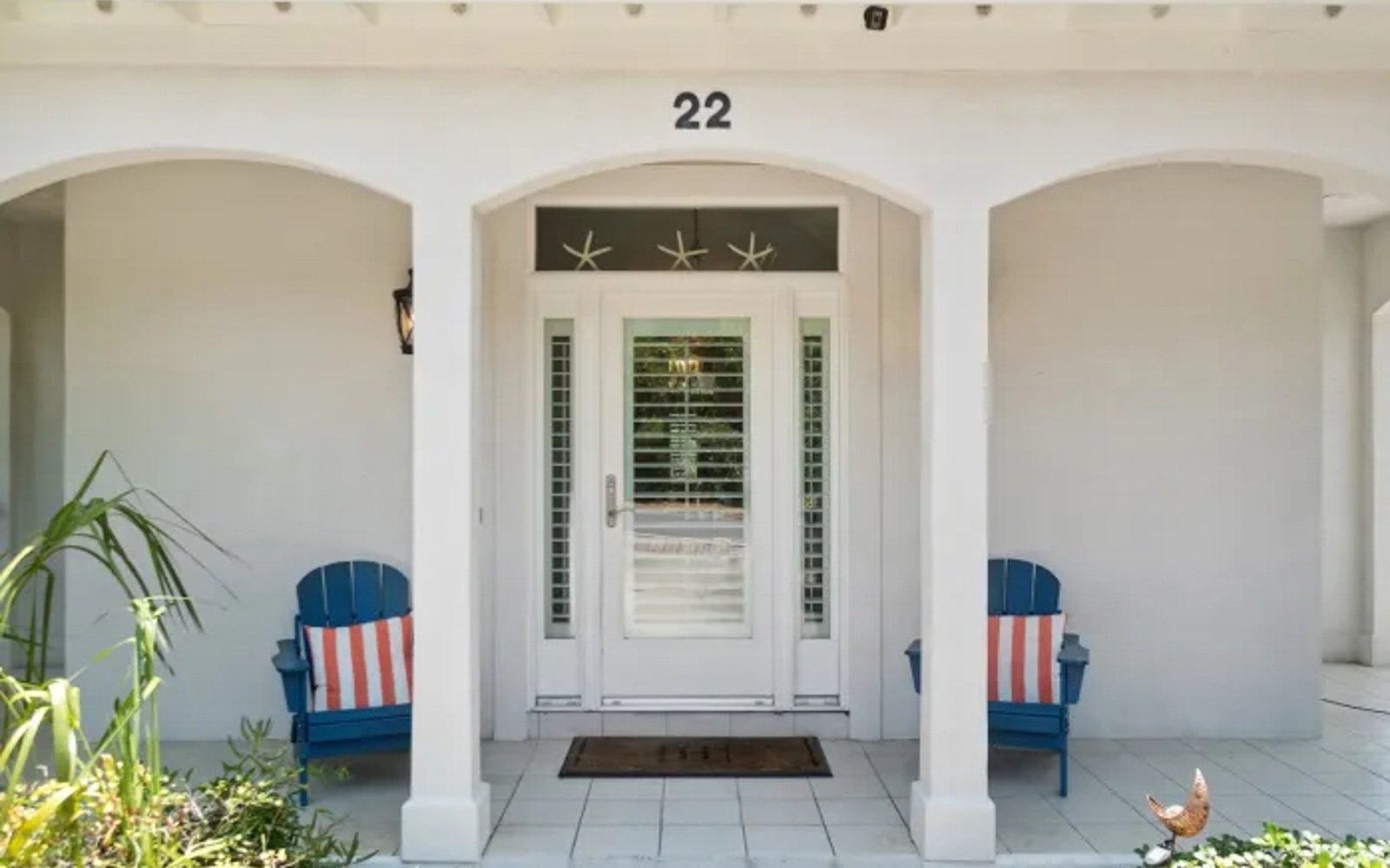 Your coastal retreat awaits behind this charming entrance with cheerful blue chairs and nautical starfish touches welcoming you home.