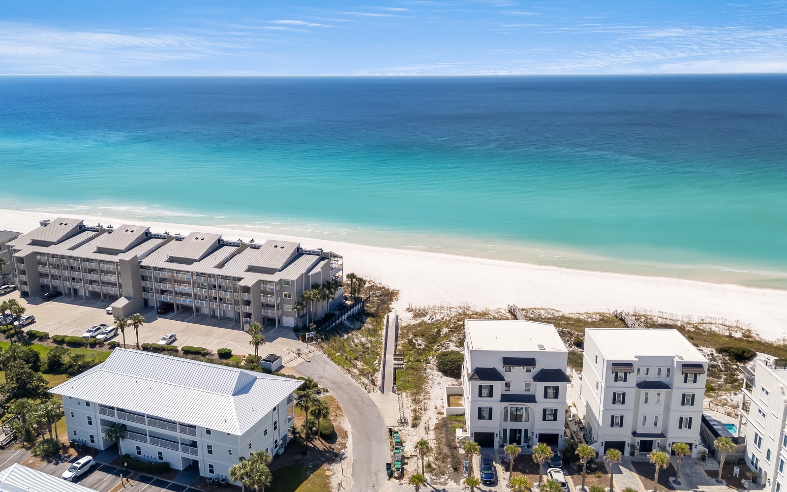 Stunning beachfront property showcasing pristine white sand and crystal-clear turquoise waters stretching to the horizon.