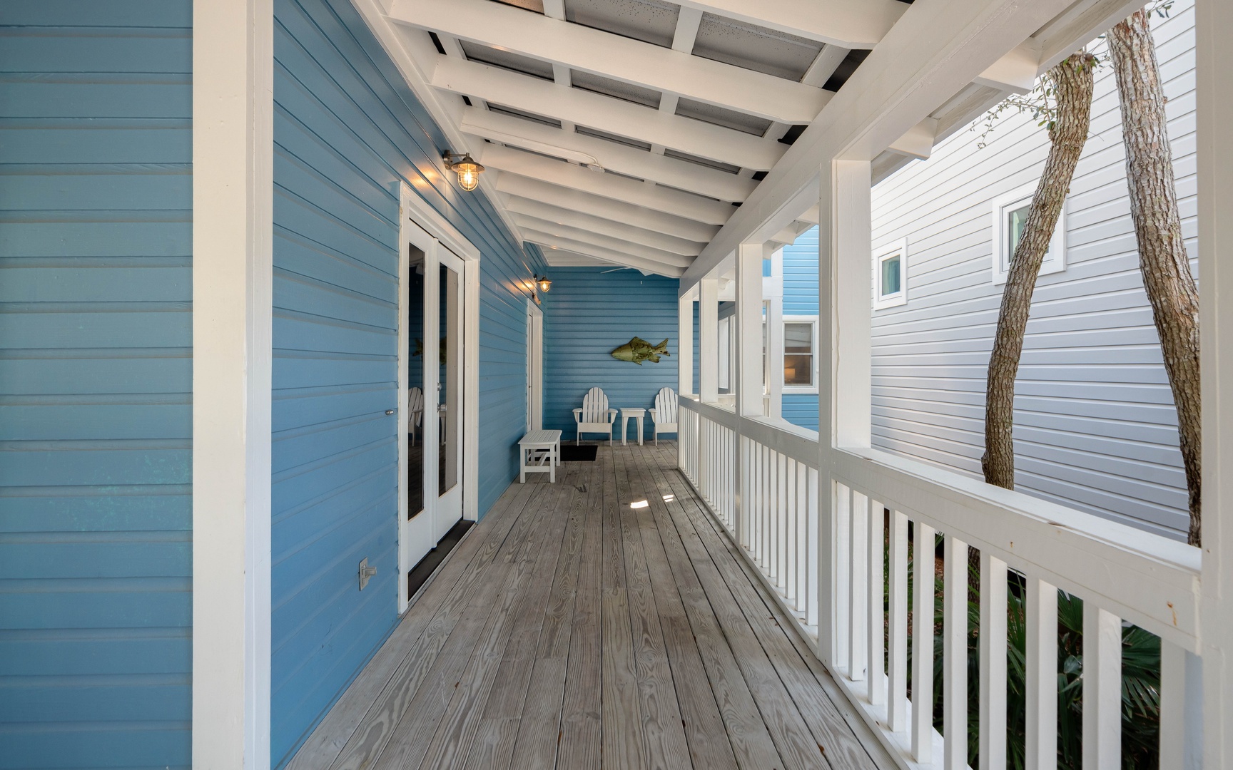 Step onto your private covered porch where coastal charm meets relaxation—Adirondack chairs await under twinkling lights for peaceful morning coffee or sunset conversations.