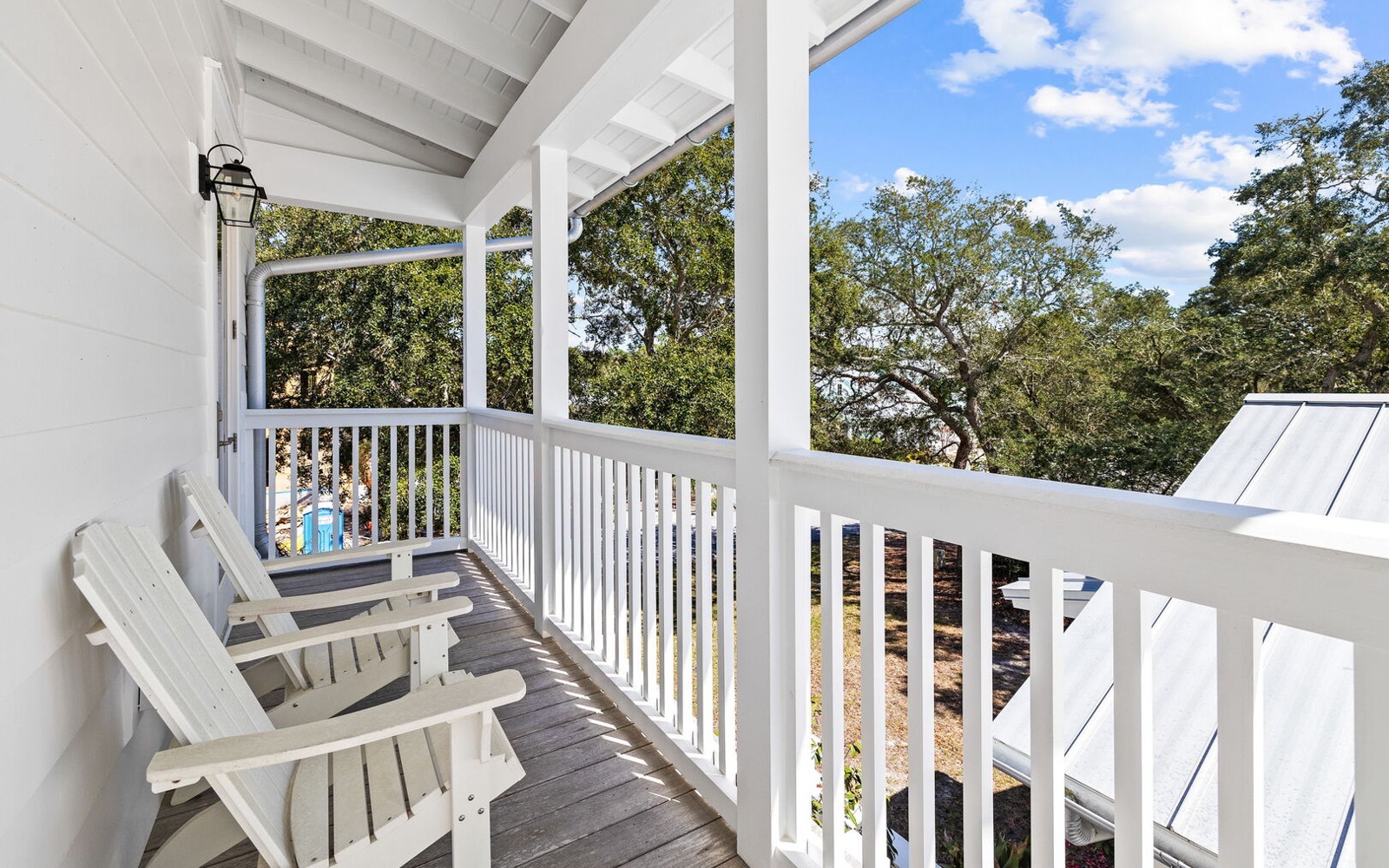 Relax in your peaceful balcony sanctuary with comfortable seating overlooking lush treetops and blue skies.