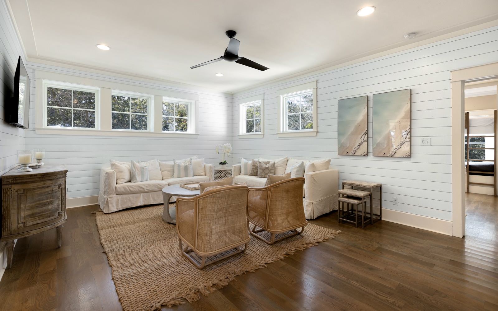 Unwind in your bright coastal-style living room with plush seating, warm wood floors, and charming shiplap walls that create the perfect retreat.