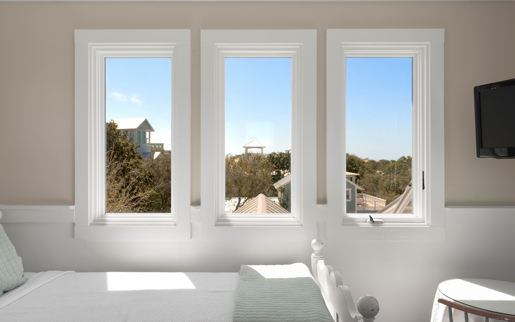 Wake up to peaceful mornings in your bright bedroom, where three picture windows frame leafy rooftops and blue skies.