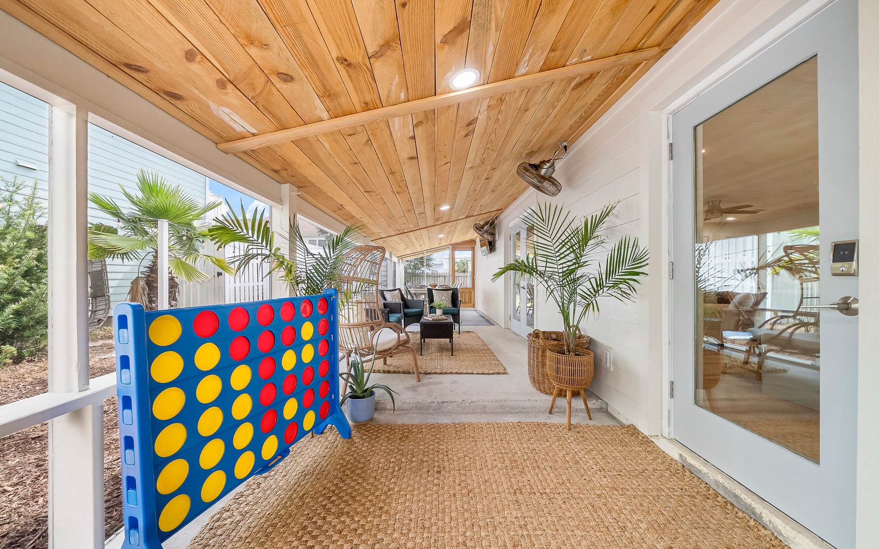 Your covered patio brings coastal charm with warm wood ceilings, tropical plants, and fun games for memorable evenings.