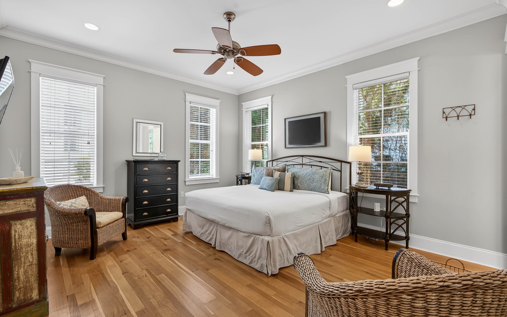 Relax in your serene bedroom featuring elegant hardwood floors, natural light from multiple windows, and a ceiling fan to keep you comfortable year-round.