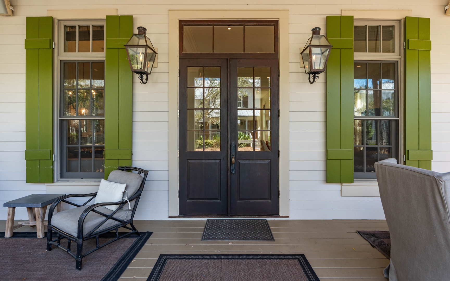 Charming farmhouse entrance with welcoming double doors, vintage lanterns, and comfortable porch seating for peaceful morning coffee or evening relaxation.