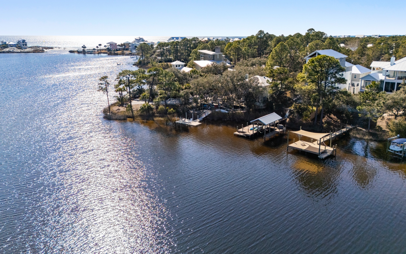Aerial view of waterfront property surrounded by sparkling waters, private docks, and peaceful coastal neighborhood.