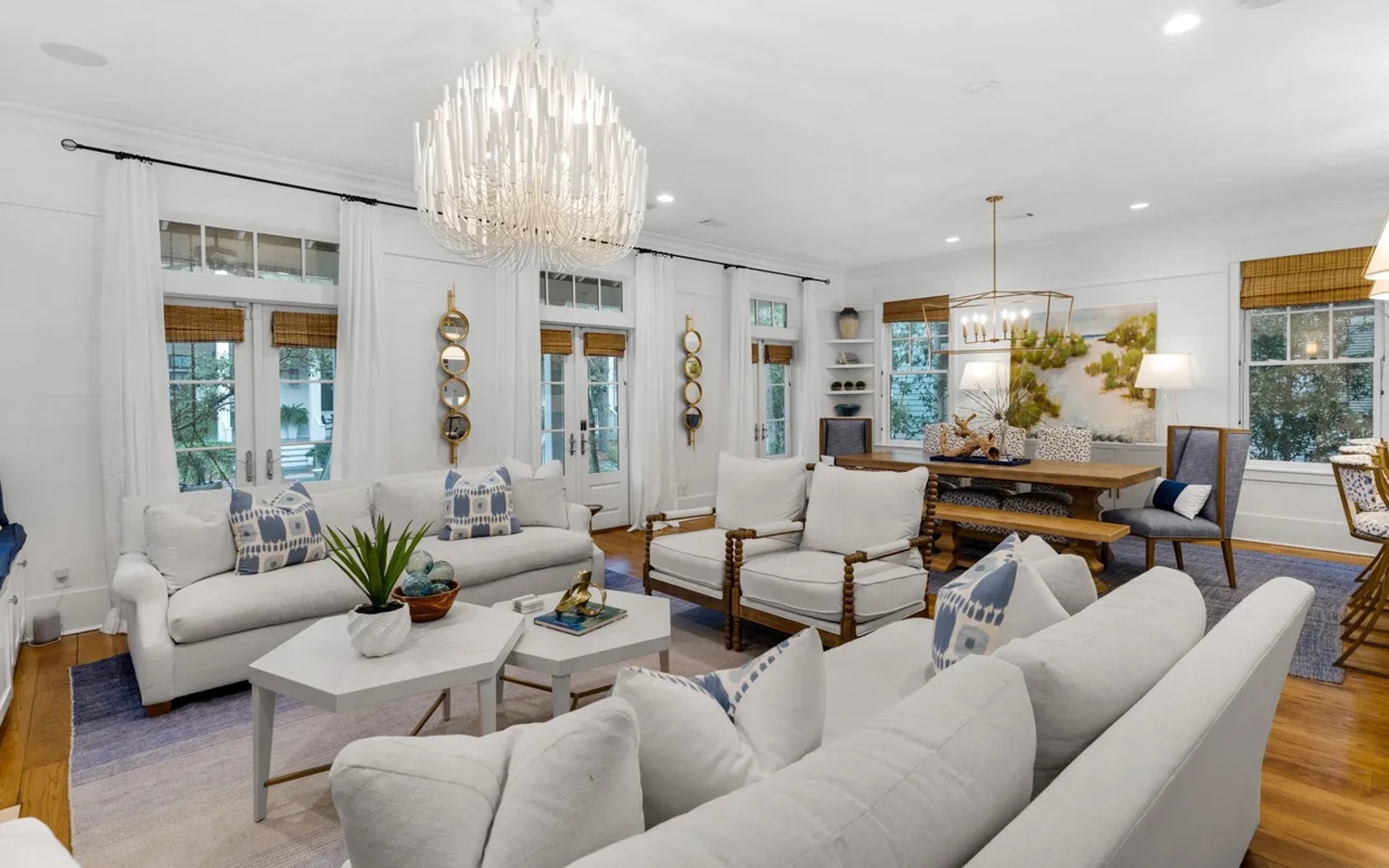 Sink into plush sofas beneath the stunning chandelier, where natural light floods through bamboo shades creating your perfect retreat.