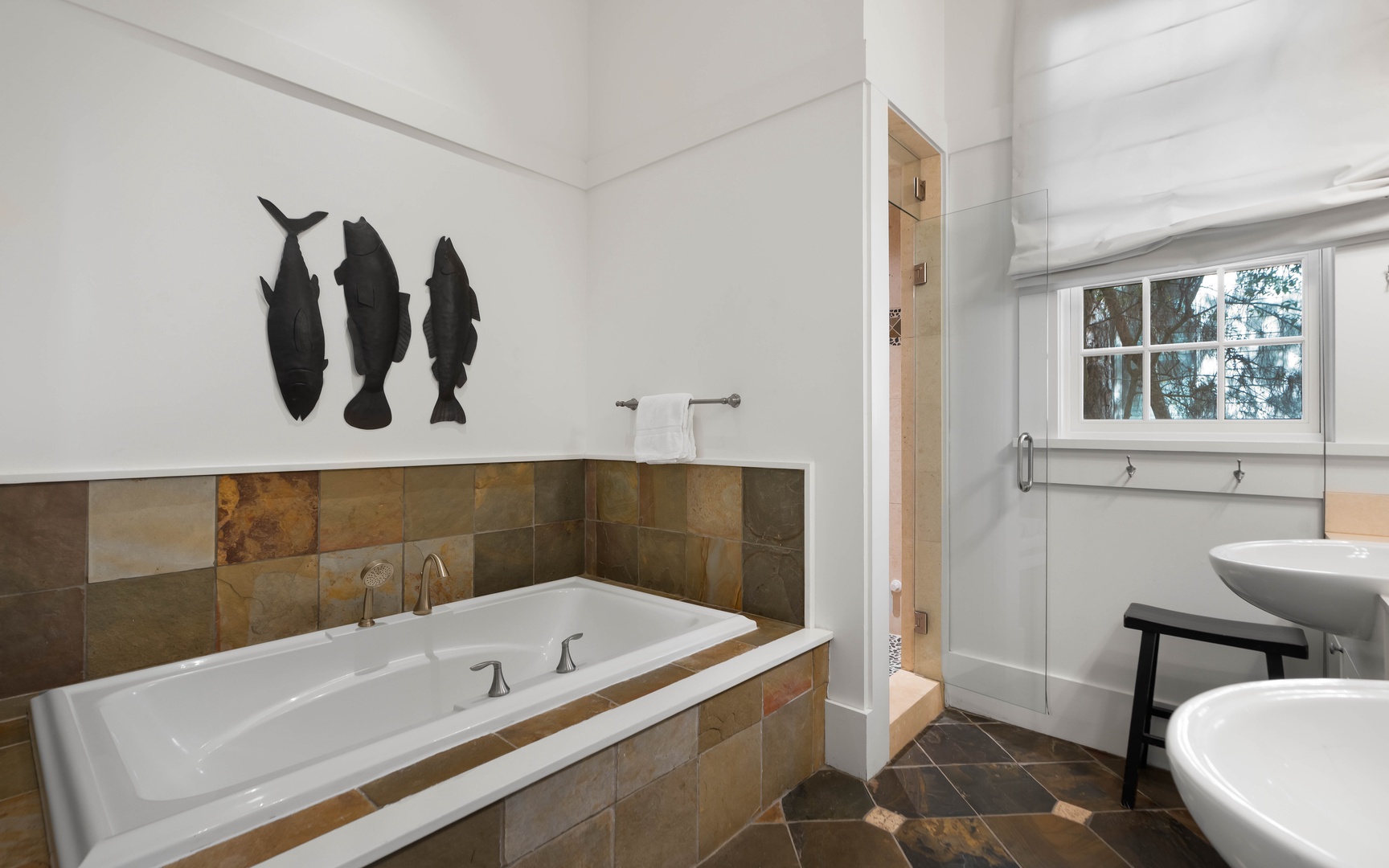 Unwind in your spa-like bathroom with a deep soaking tub surrounded by elegant stone tiles and artistic fish silhouettes.