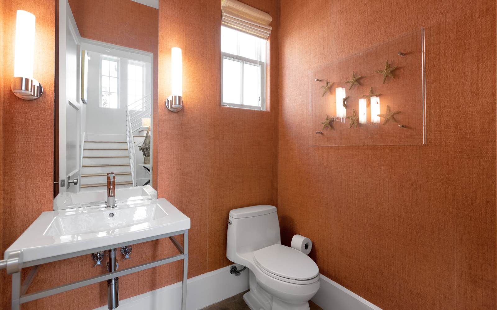 Step into your stylish powder room featuring warm coral walls and modern fixtures for your comfort.