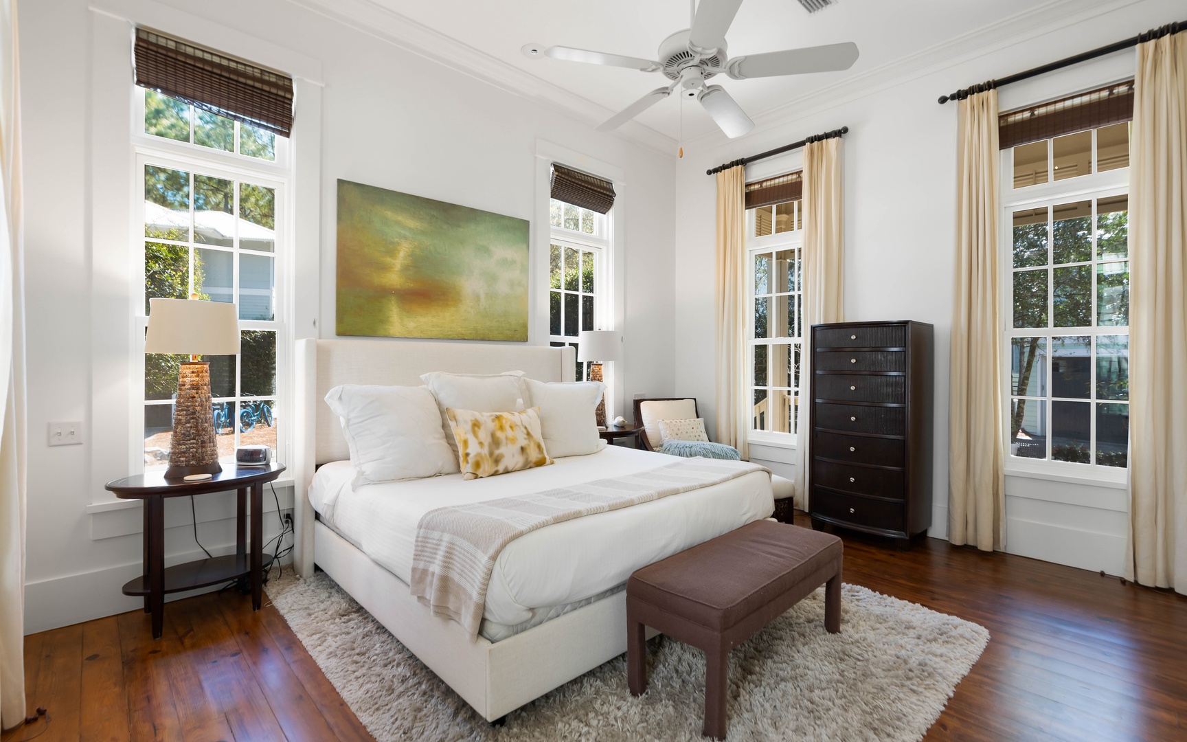 Unwind in your serene master bedroom with crisp linens, original hardwood floors, and peaceful garden views through charming French doors.
