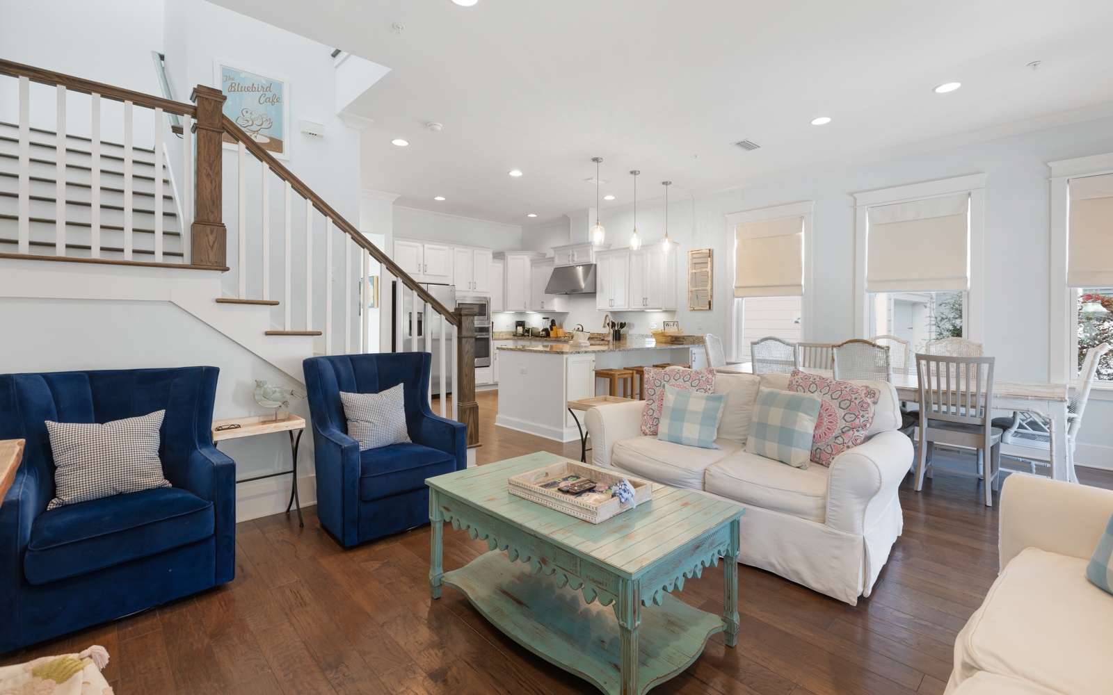 Settle into your coastal-inspired open living space where navy chairs and mint accents create perfect harmony for relaxing after beach days.