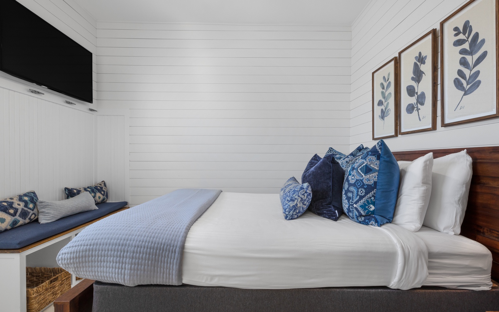 Sink into crisp white linens and plush blue pillows in your serene bedroom retreat, complete with coastal artwork and modern amenities.