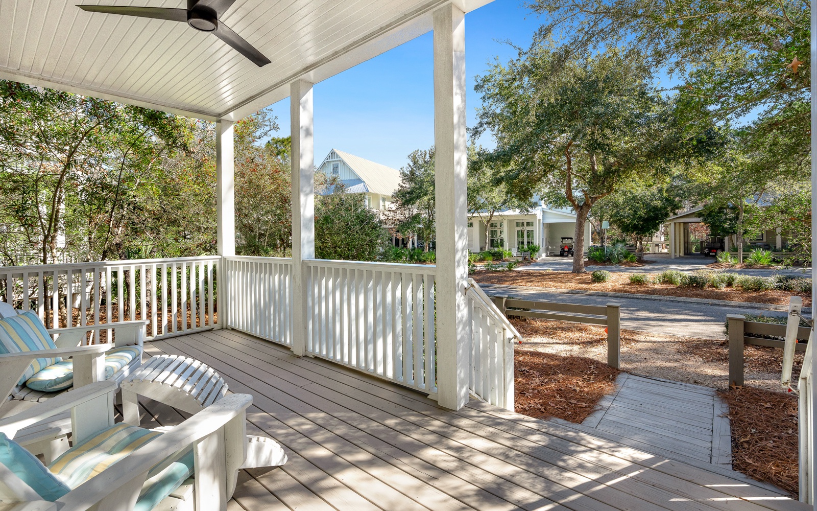 Relax on your private covered porch with ceiling fan, where comfortable seating awaits and peaceful neighborhood views create the perfect morning coffee spot.
