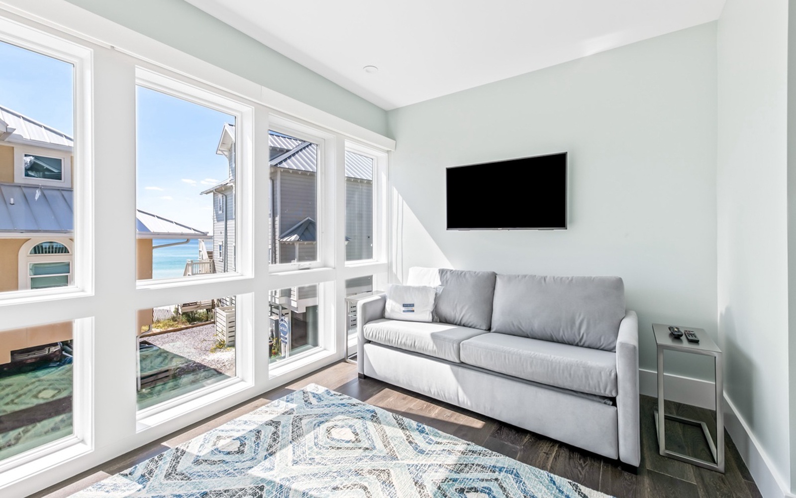 Unwind on your plush sofa while enjoying stunning water views through floor-to-ceiling windows in this bright, coastal retreat.