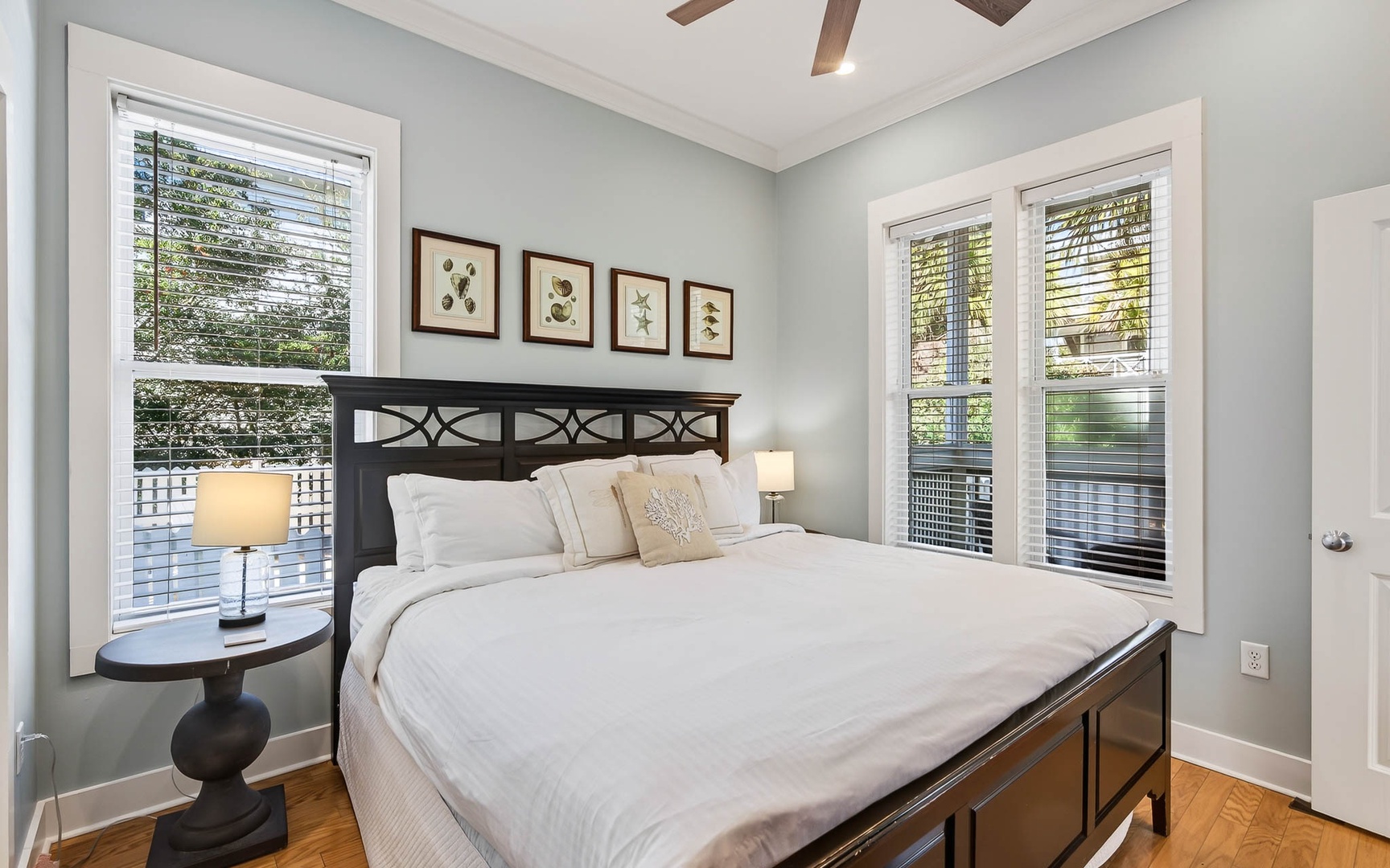 Wake up in your serene bedroom where soft morning light filters through windows, illuminating crisp white linens on your elegant wooden bed.