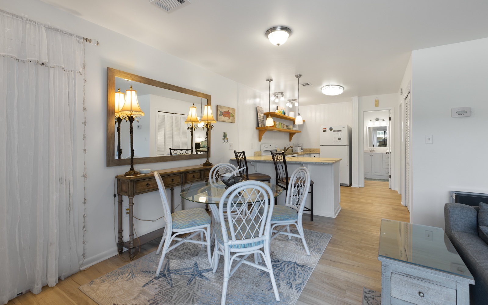 Step into your bright dining space where coastal charm meets comfort—perfect for sharing meals around the glass table.
