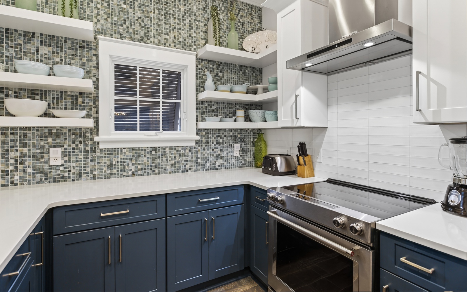 You'll love cooking in this stylish kitchen featuring beautiful mosaic tile backsplash, navy cabinets, and modern stainless steel appliances.