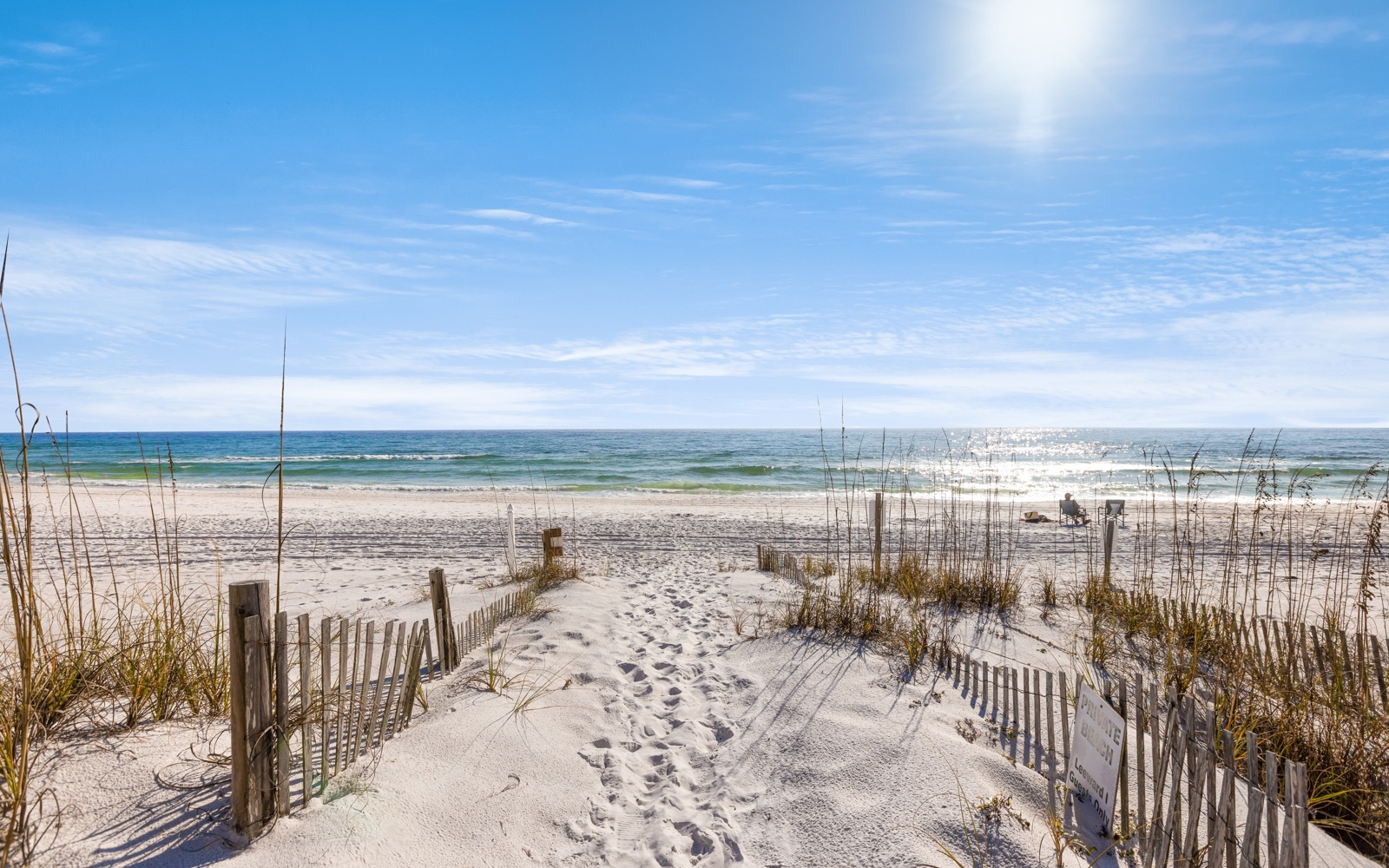 Pristine beach with white sand dunes and walking path leading to the ocean waves