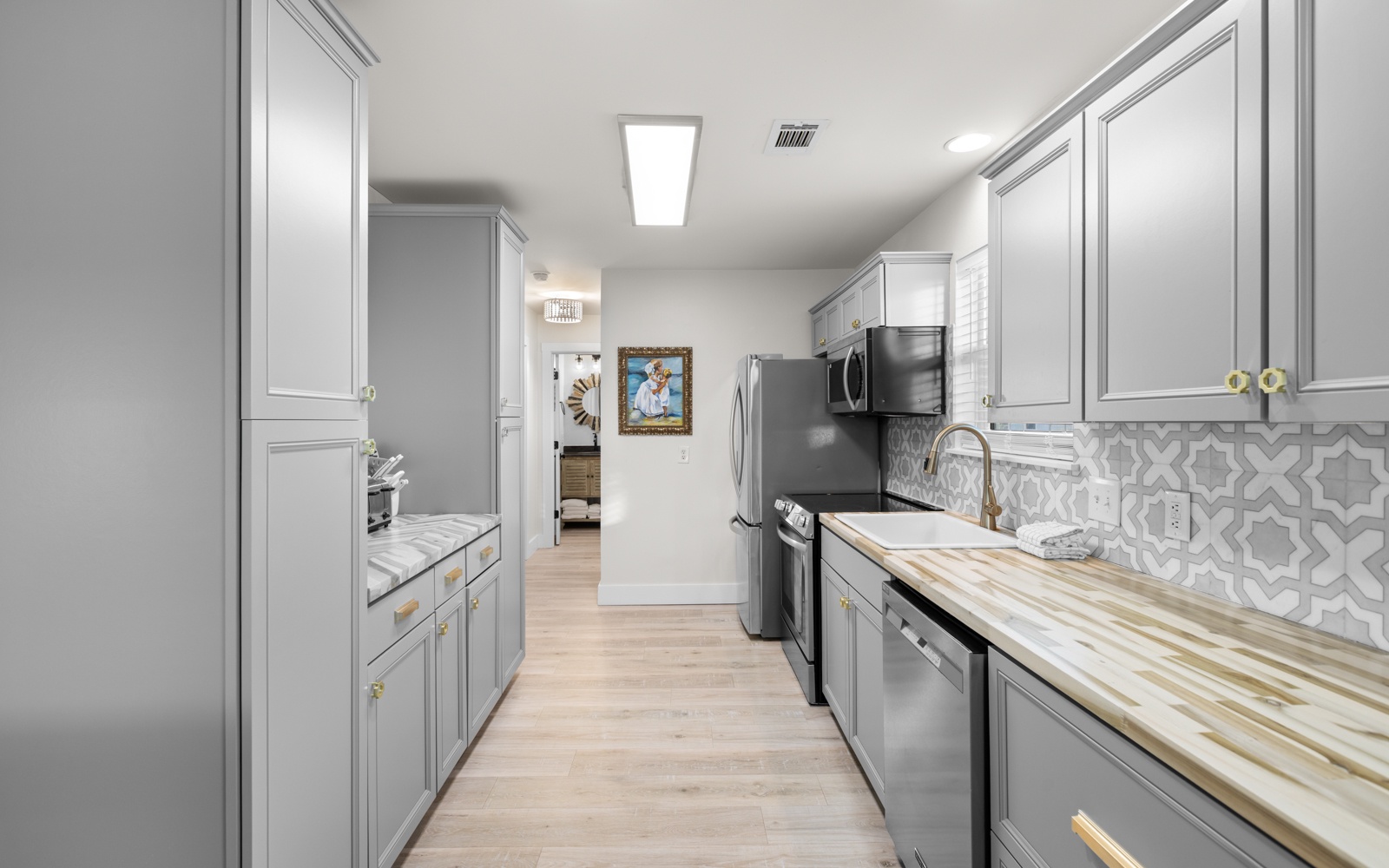 Your stylish galley kitchen features elegant grey cabinetry, modern appliances, and beautiful patterned backsplash—perfect for preparing memorable meals during your stay.