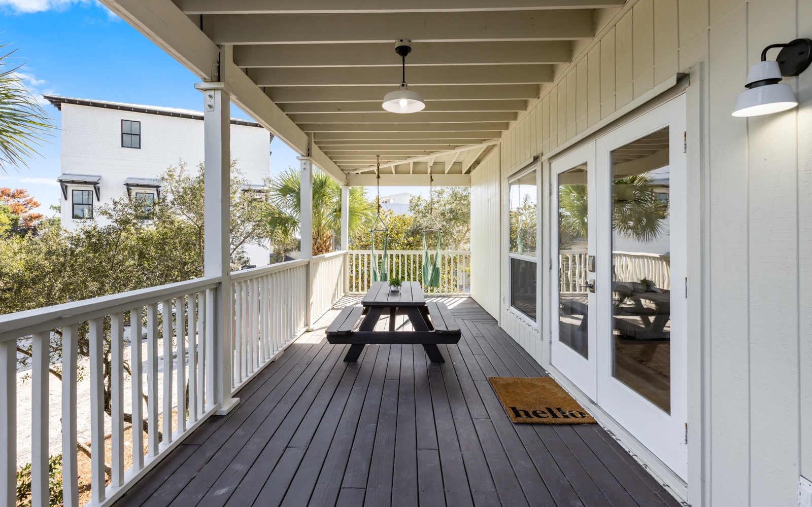 Step onto your private covered deck with dining table and tropical views through palm trees and neighboring homes.