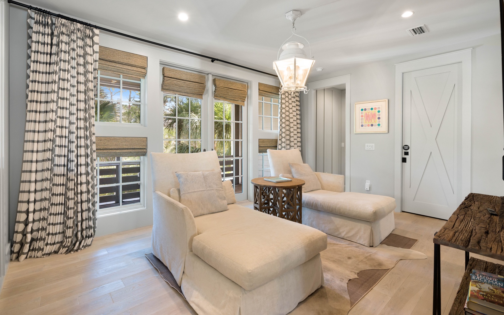 Sink into plush armchairs in this elegant living room, where natural light streams through bamboo shades and tropical views await beyond.