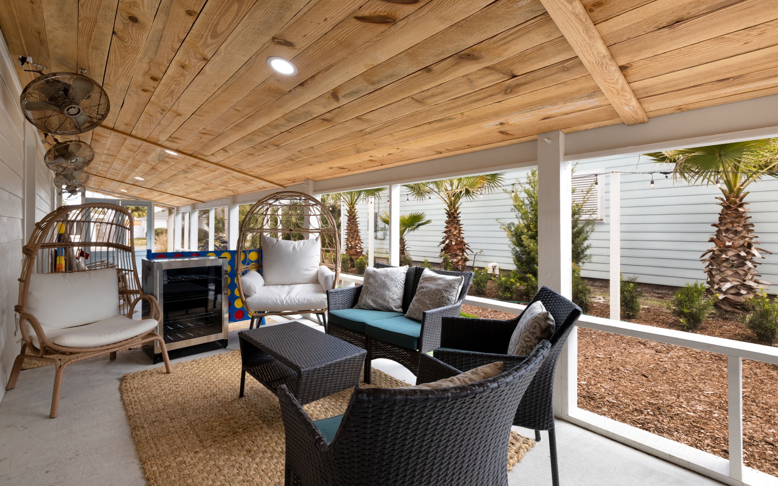 Settle into your private covered patio where rustic wood beams frame comfortable seating and cooling fans create the perfect outdoor retreat.
