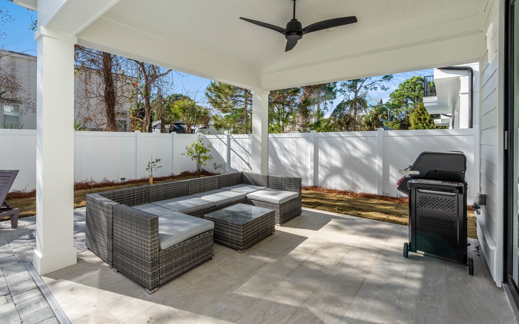 Your private covered patio features comfortable seating and a BBQ grill, perfect for outdoor dining and relaxing under the ceiling fan.